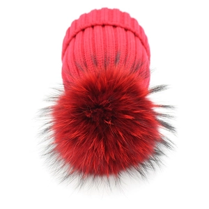 Berretto chic in maglia rossa da donna con un grande pompon in finta pelliccia morbida