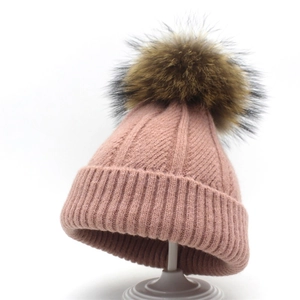 Women's pink knit beanie with fluffy faux fur pom pom and ribbed cuff for winter warmth