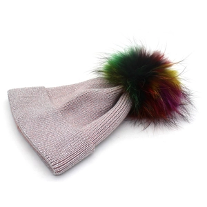 Détail d'un bonnet en tricot rose avec fil métallique brillant et pompon coloré en fourrure