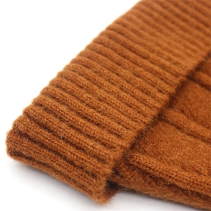 Macro detail of ginger knit wool hat showing rich ribbed texture and warm fabric fibers