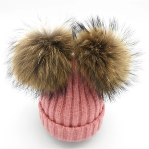 Detalle del gorro de punto rosa con dos pompones grandes de piel natural muy suaves