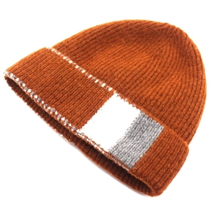 Detail of rust red knit beanie showing ribbed texture and decorative patch detail