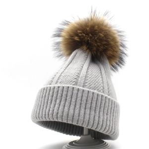 Women's light grey knitted winter beanie with a large dark brown faux fur pom pom