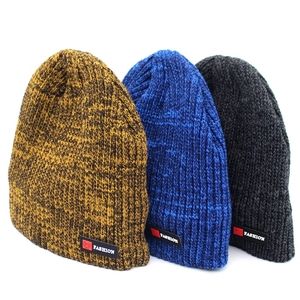 Detailed close-up of ribbed knit beanies in mustard, blue, and grey with fashion labels