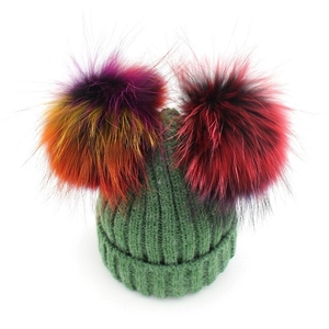 Green ribbed knit wool beanie featuring two vibrant colorful faux fur pom-poms for winter