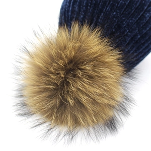 Detail of navy knit beanie with large fluffy faux fur pompom and textured ribbing