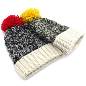 Detailed knit texture of thick wool hats with mixed colors and fluffy pom-pom accents