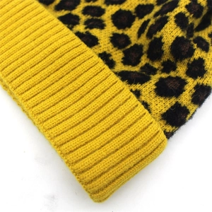 Detailweergave van de gele gebreide wintermuts met luipaardprint en dikke ribstructuur