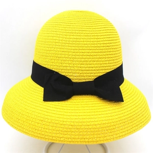 Dettaglio della trama intrecciata gialla del cappello da sole con fiocco in nastro nero
