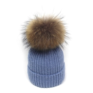 Detailansicht der hellblauen Rippstrickmütze mit einem großen, flauschigen Pelz-Pompon