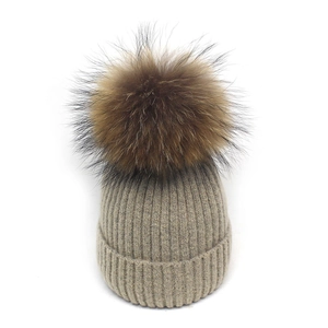 Detailansicht der khakifarbenen Strickmütze mit hochwertigem braunem Pelzbommel