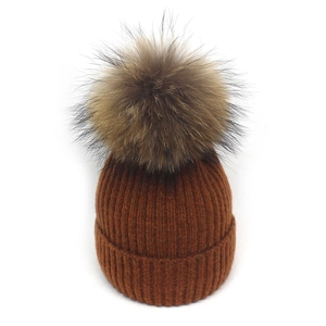 Detailaufnahme der rostbraunen Strickmütze mit flauschigem, großem Kunstfell-Bommel