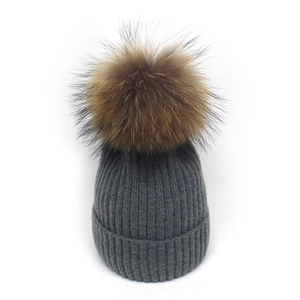 Detail der grauen Strickmütze mit flauschigem braunem Waschbärpelz-Bommel oben drauf