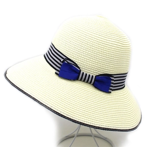 Detail of summer straw hat featuring black and white striped ribbon and dark blue bow