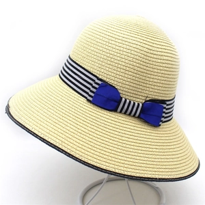 Detail of summer straw hat with black white striped band and vibrant blue double bow