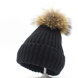 Nahaufnahme der schwarzen Strickmütze mit einem großen, flauschigen braunen Bommel