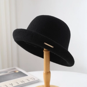 Elegante bombín de fieltro de lana negra con placa dorada sobre soporte de madera