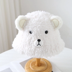 Cute white plush bear hat with round ears and embroidery on a wooden stand