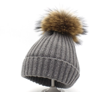 Detailaufnahme der grauen Rippstrickmütze mit einem flauschigen Echtpelz-Bommel oben