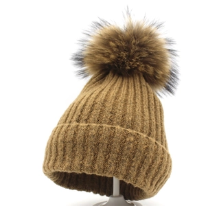 Detailaufnahme einer braunen Rippstrick-Wintermütze mit einem großen flauschigen Bommel