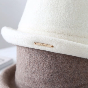 Primer plano de sombrero de lana elegante con placa dorada en el detalle del ala curvada