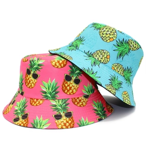 Detail view of pink and blue reversible sun hats with cartoon pineapple patterns