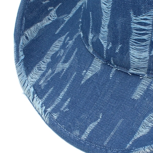 Detail of distressed dark blue denim fedora showing ripped texture and raw edge finish