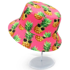Close-up of bright pink bucket hat with tropical pineapple patterns on a white stand