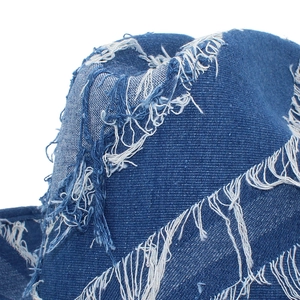 Detailed macro view of distressed blue denim fabric with fringe and worn-out textures