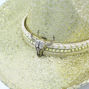 Dettaglio cappello da cowboy con paillettes dorate, testa di toro e cinturino a borchie