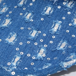 Detail of distressed blue denim hat featuring leaf belt with silver sequins and glitter