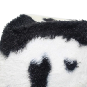 Detailed close-up of fluffy black and white cow print plush texture on a warm hat
