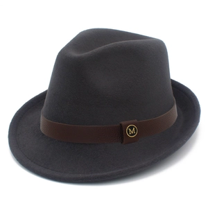 Detail of dark grey wool fedora hat with brown leather band and gold M logo badge