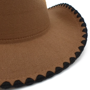 Dettaglio di cappello in feltro cammello con cuciture nere e trama di qualità