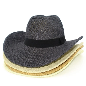 Dettaglio di cappelli da cowboy in paglia intrecciata in vari colori con nastro