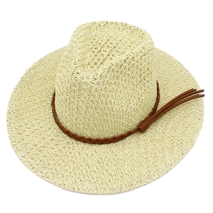 Detailed view of the straw hat with a braided brown strap and decorative tassel accents