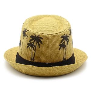 Detail of summer straw fedora hat featuring black palm tree prints and a wide black band