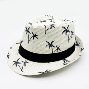 Detailed weave texture of a white straw fedora with blue palm tree print and black ribbon