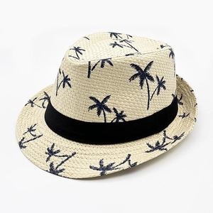Close-up of beige straw fedora hat featuring dark blue palm tree patterns and black ribbon band