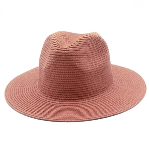 Close-up of coral pink straw sun hat with fine woven texture and classic wide brim