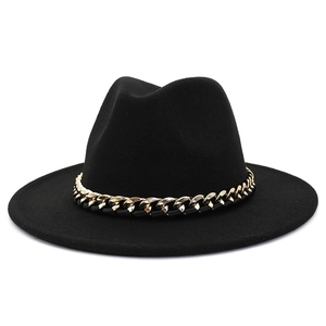 Détail d'un chapeau fedora noir en laine avec une chaîne décorative en métal doré épais