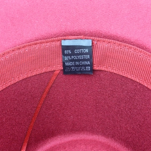 Detailed macro view of the inner sweatband and 65% cotton blend care label on red fedora