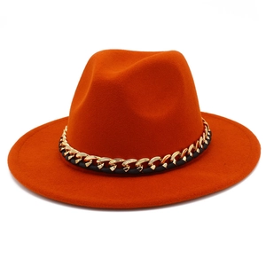 Vue détaillée d'un chapeau fedora orange avec une chaîne dorée et un ruban en cuir noir