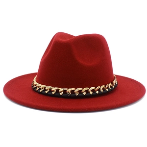 Détail d'un chapeau fedora rouge avec chaîne dorée et ruban tressé noir élégant