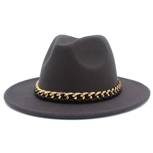 Détail d'un chapeau fedora en laine gris foncé avec chaîne dorée et cuir noir tressé