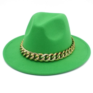 Detail of a bright green fedora hat featuring a chunky gold metal chain on a wide brim