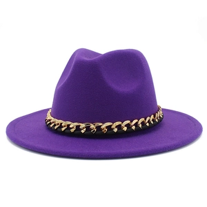 Chapeau fedora en laine violet foncé avec une chaîne dorée sur fond blanc neutre