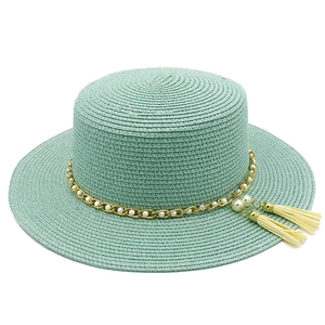 Dettagli del cappello di paglia verde menta con elegante catena d'oro e nappe di perle