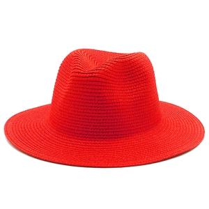 Detailed view of bright red straw Fedora hat with intricate spiral woven texture and brim