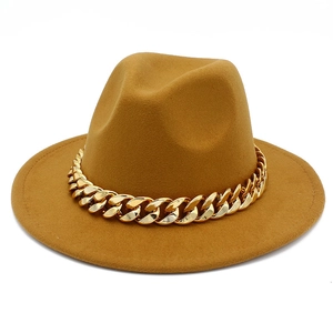 Detail shot of the golden Cuban link chain on a ginger yellow wide brim fedora hat
